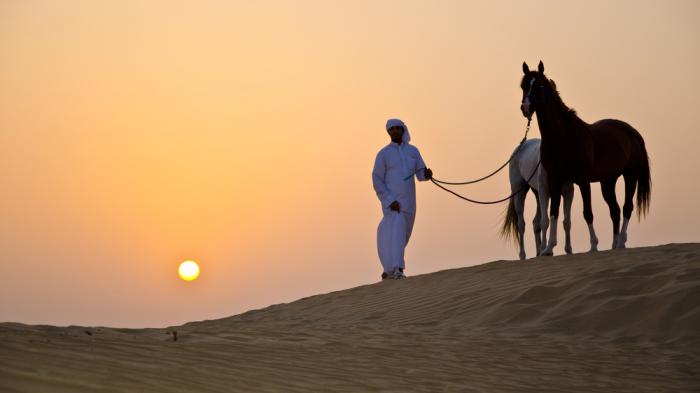 Zwei Araber mit Mensch in der Wüste mit Sonnenuntergang