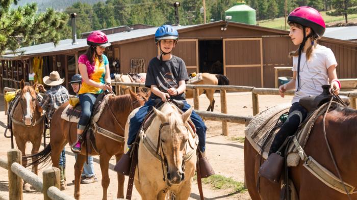 Kinder beim Westernreiten auf Pferden während Reiterferien für Kinder
