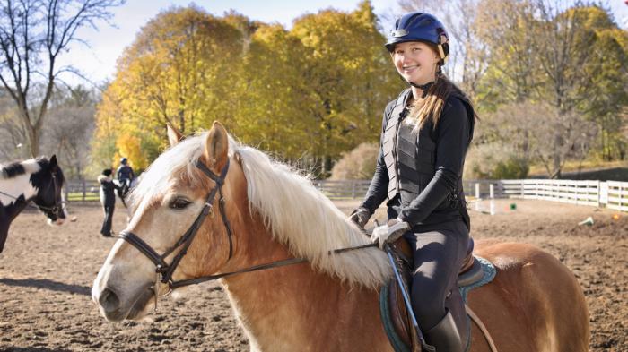 Reiterin mit Schutzweste auf Pferd für mehr Sicherheit beim Reiten 