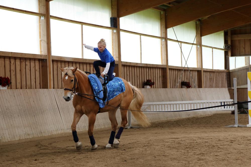 Reiterin bei einer Übung beim Voltigieren auf einem Pferd