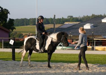 Reiterin auf Pferd erhält Reitunterricht für Erwachsene von einer Reitlehrerin